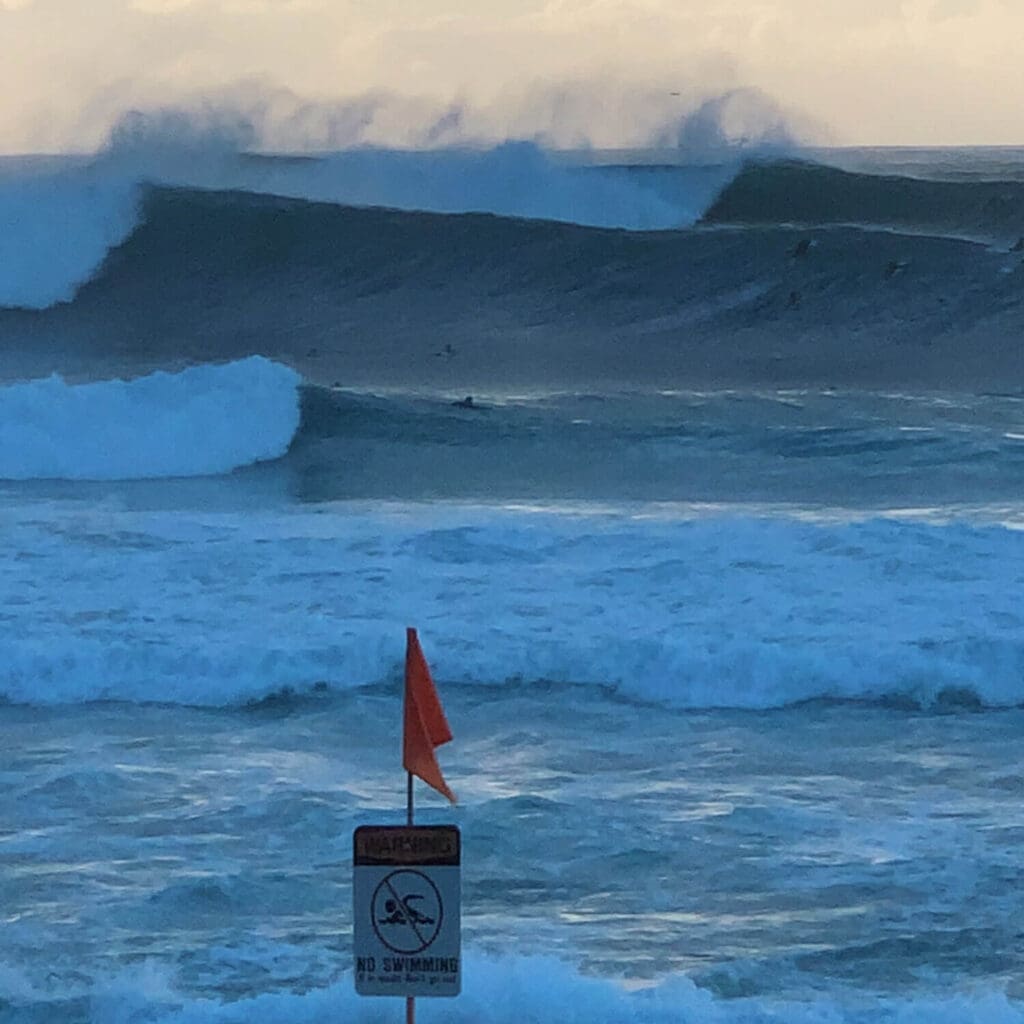 Surfers surfing massive waves at Pipeline on the North Shore of Oahu