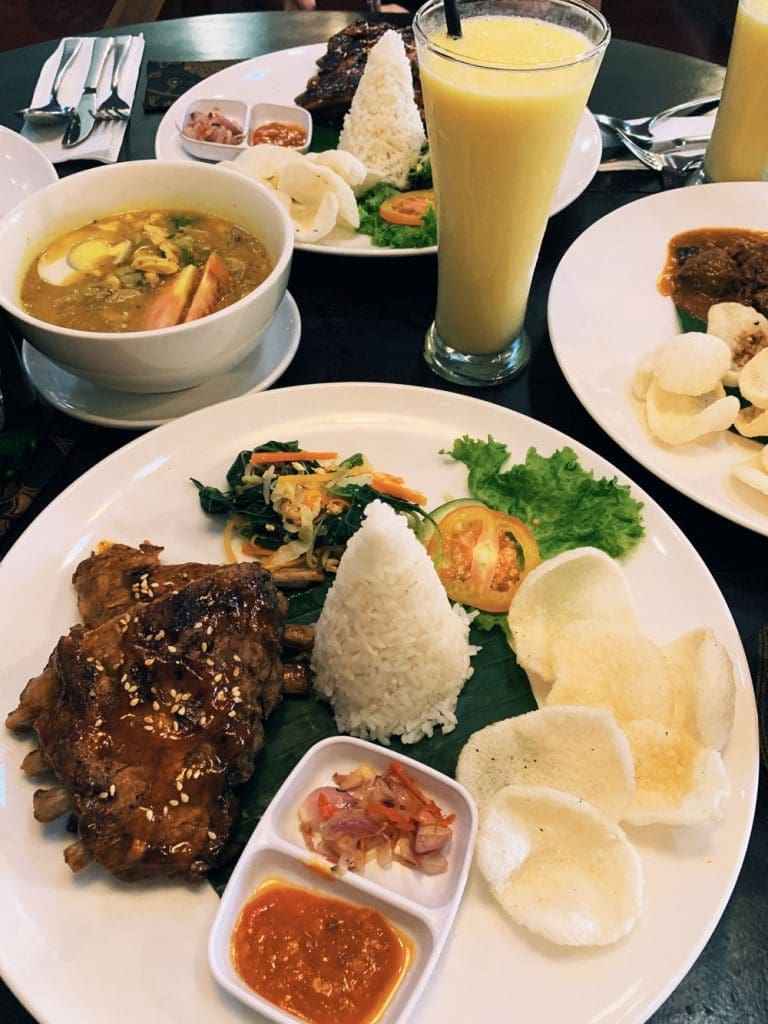 Local Balinese style lunch in Ubud with rice, ribs, sambal, rice crackers, soup, and smoothie