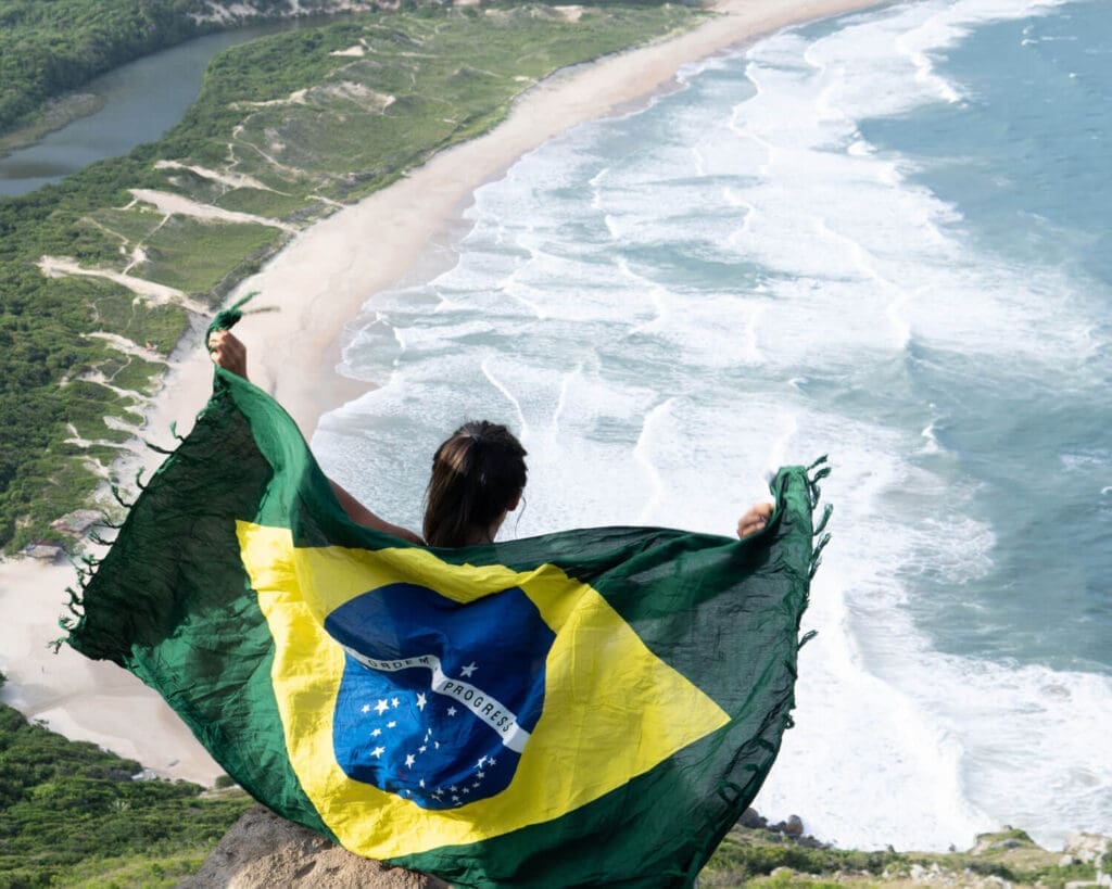 Girl holding flag of Brazil above a beach