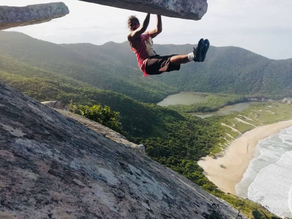 Climber hanging on to a rock overlooking beach