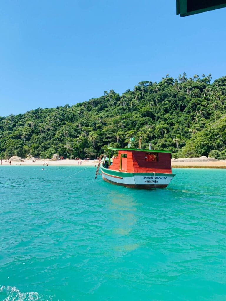 Boat in blue water and lush greenery in background