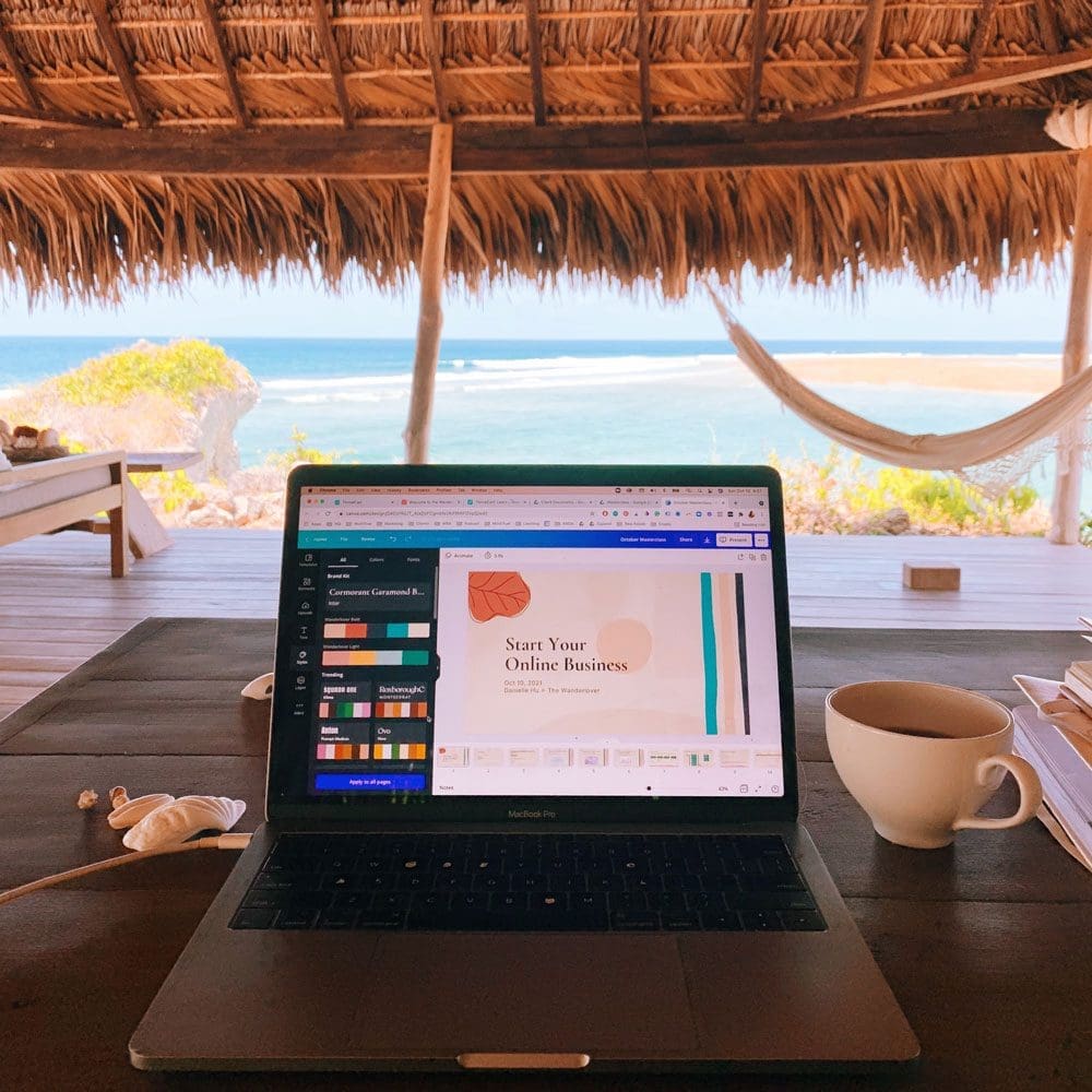 A macbook computer showing the start your business intensive with a tropical beach in the background