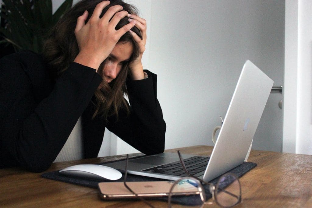 Entrepreneur stares at a laptop with head in her hands, struggling with limiting beliefs