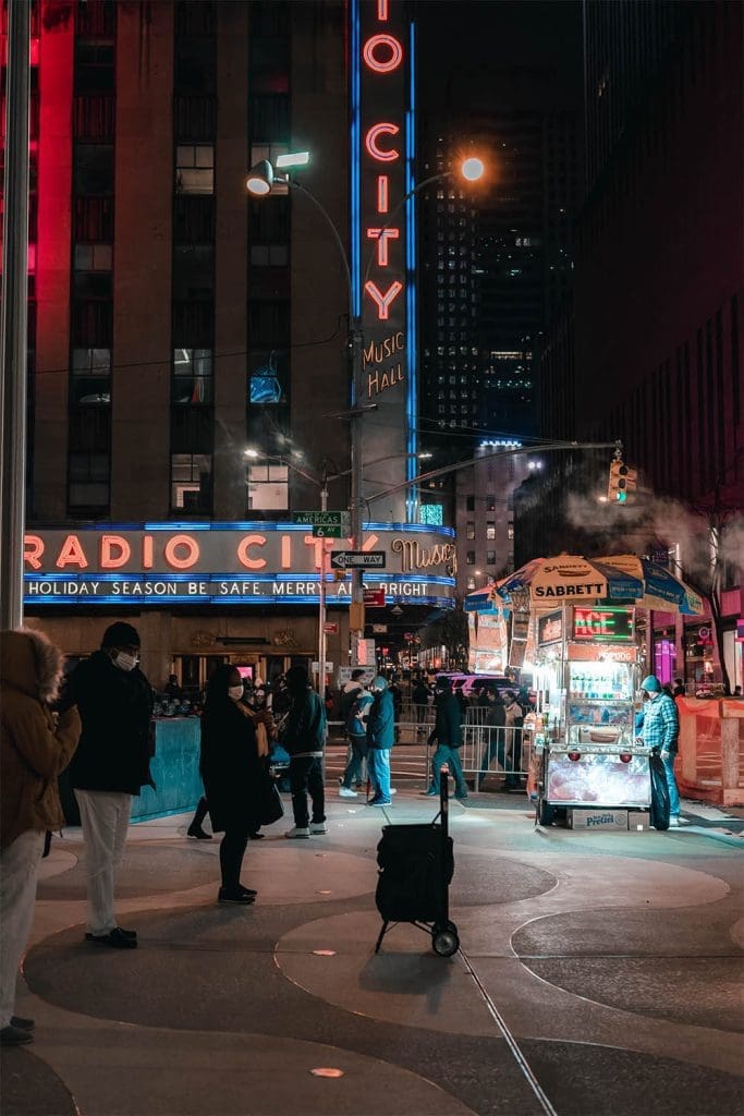 Street vendors and people walk the streets outside of radio city new york