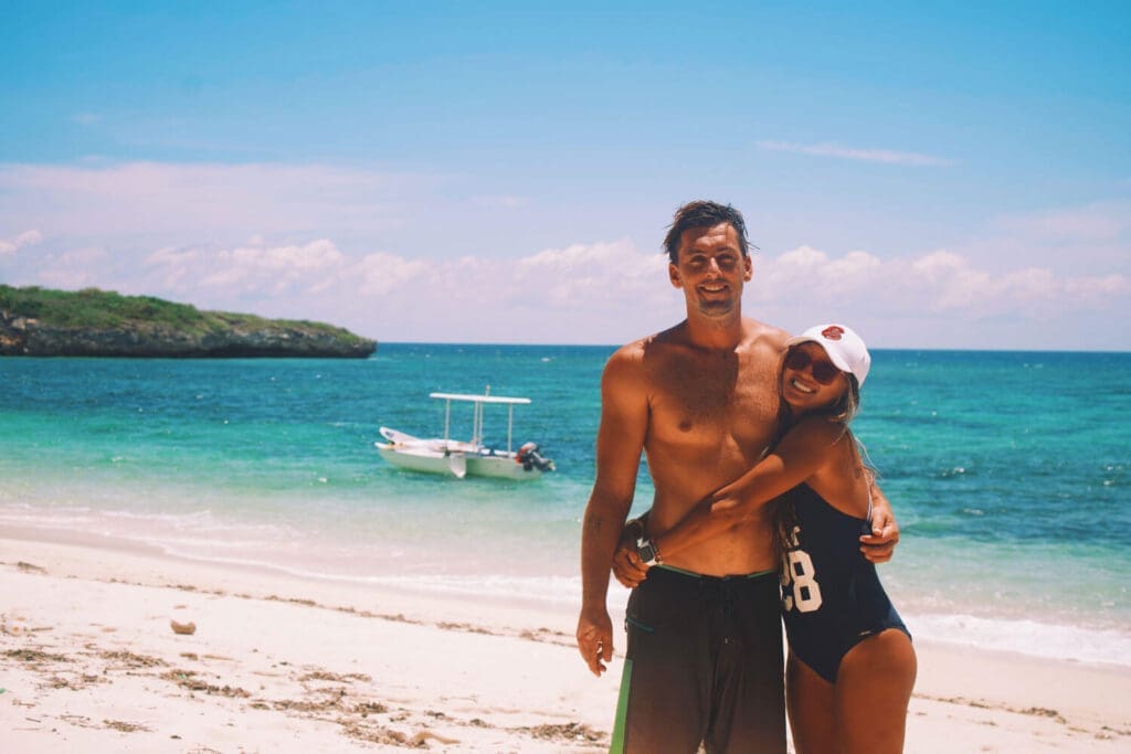 Man and woman hugging on a beach smiling at the camera