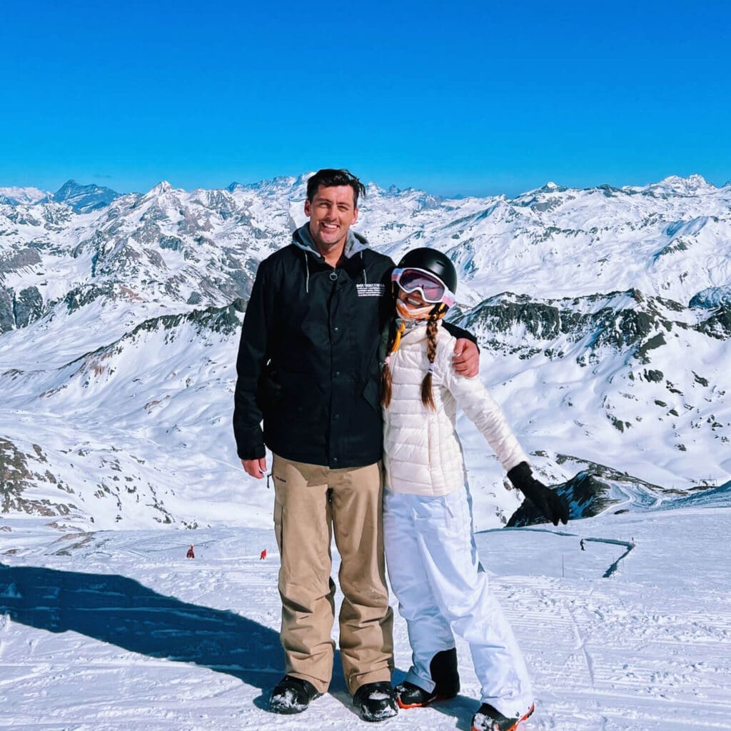 Man and woman in snowboarding gear at the top of a snowy mountain