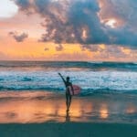 Girl holding surfboard in the sunset at a beach in Canggu