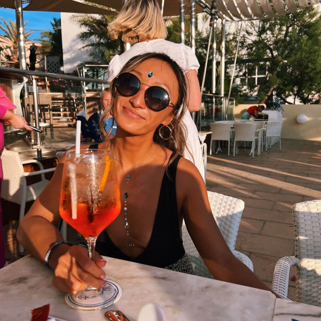 Girl with an aperol spritz smiling at the camera