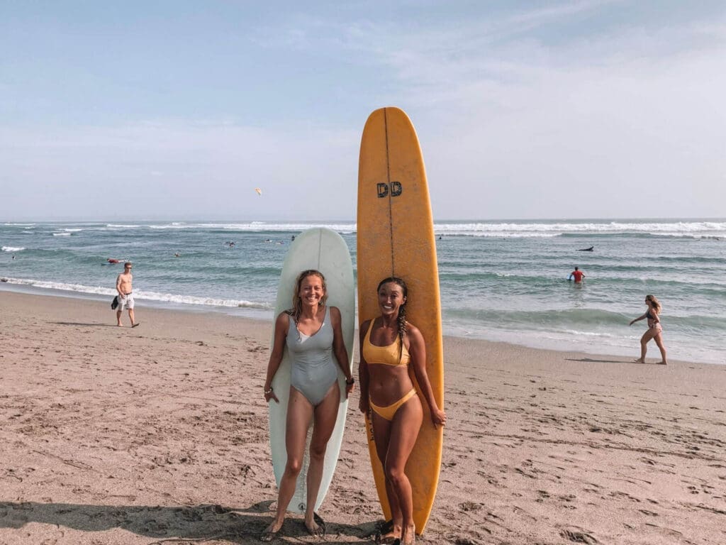 Two girls standing in front of their surfboards on a beach in Canggu Bali