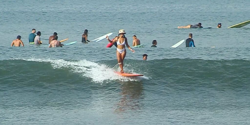 Girl surfing on a longboard in Batu Bolong with lots of people