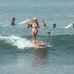 Girl surfing on a longboard in Batu Bolong with lots of people