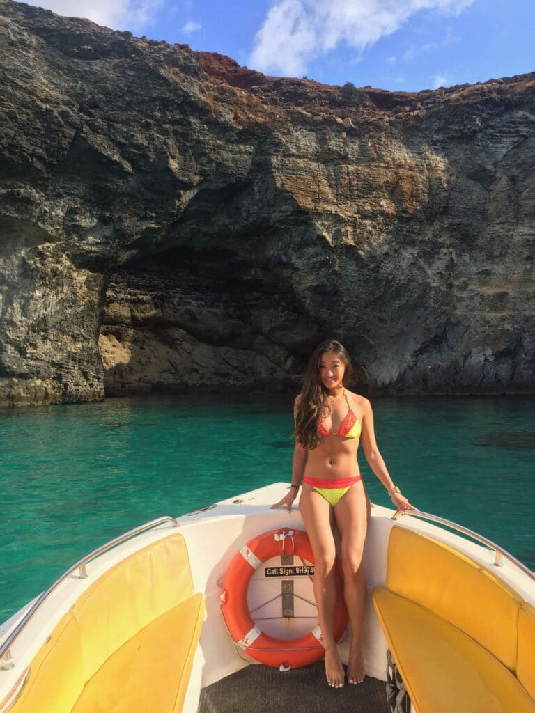 Girl standing in a boat in front of Blue Lagoon Caves