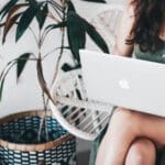 Girl working on her laptop with a plant in the background