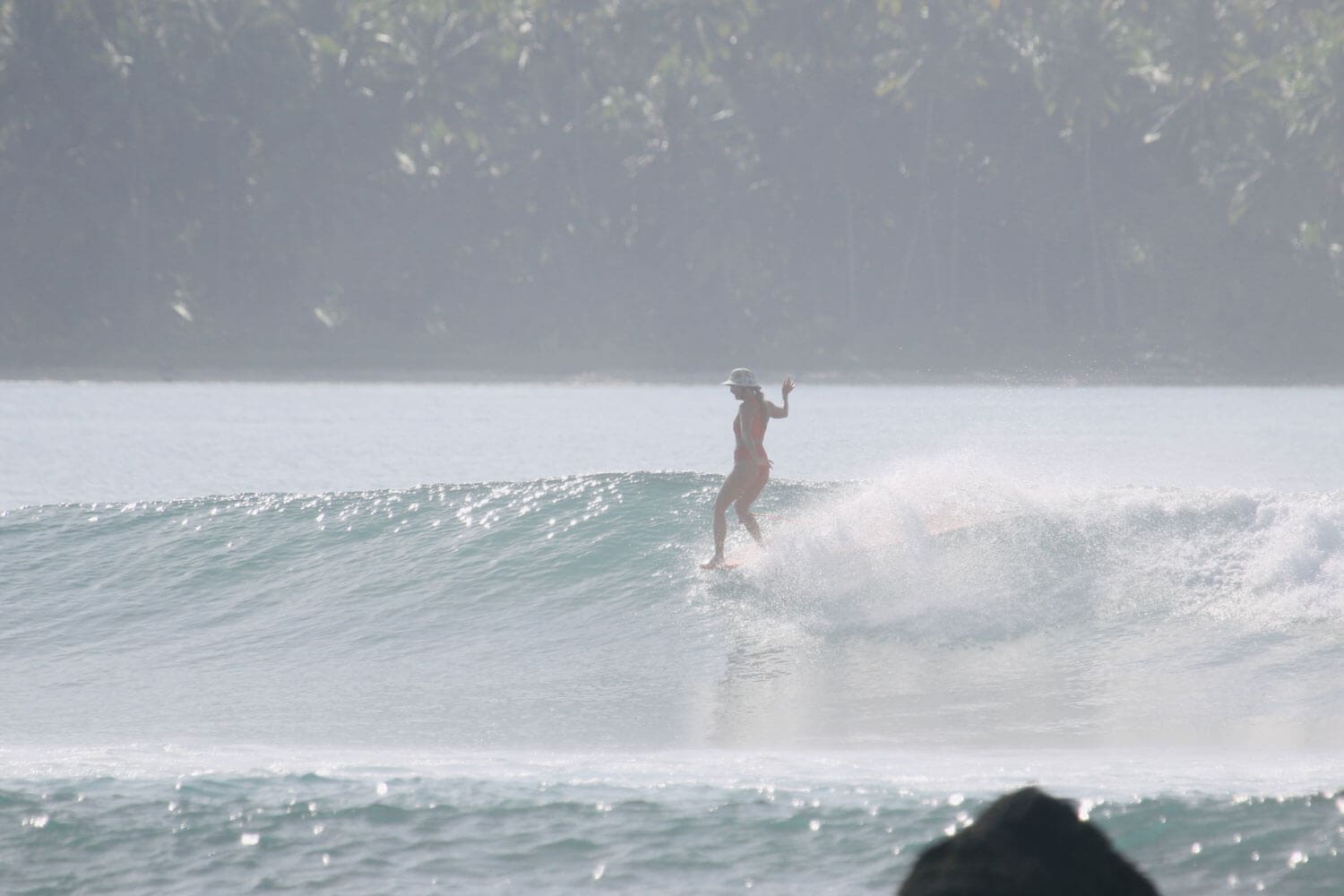 Girl hanging 5 on longboard in Nias Indonesia