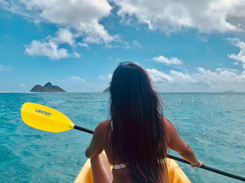 Girl kayaking with yellow oar in Hawaii