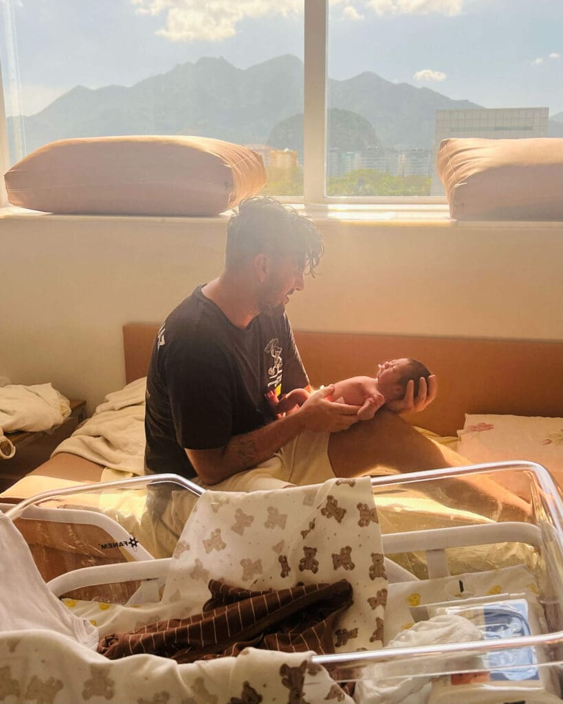 New father holding baby with mountains in the background