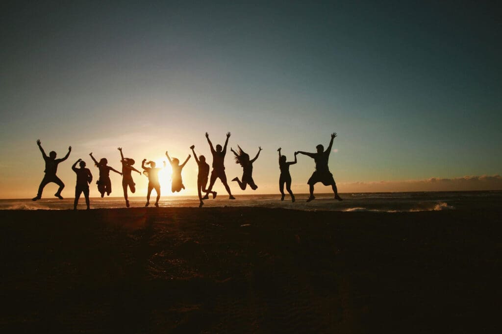 Silhouettes of a group of people jumping during sunset