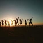 Silhouettes of a group of people jumping during sunset